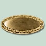 Oval messingetiket med udsmykning