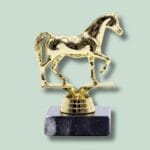 Guld hestetrofæ på marmorbase med grøn baggrund.