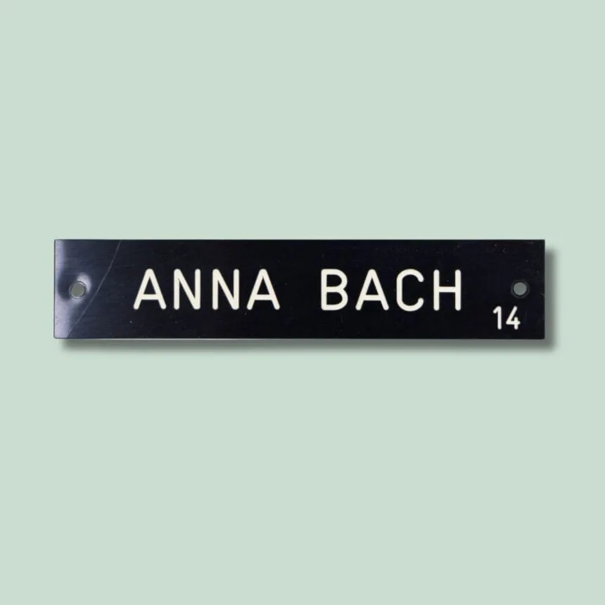 TAVLESKILT 14 -PLASTIK- GRØN Navneskilt med tekst 'Anna Bach' og tallet 14.