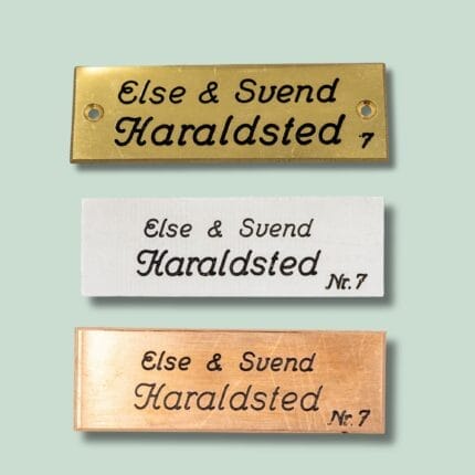 Tre navneskilte i guld, hvid og kobber.