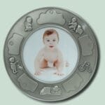 Baby i rund fotoramme med legetøjsmotiver.