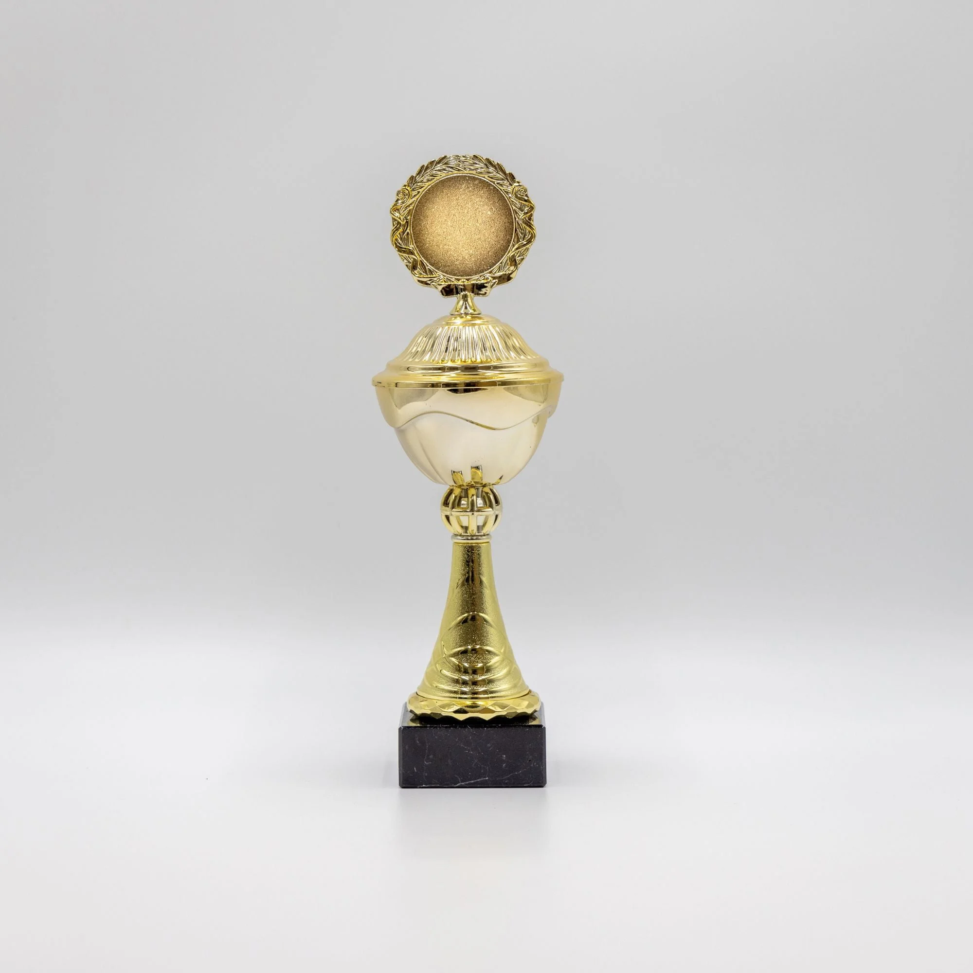Guldpokal med rund medalje på sort marmorfod