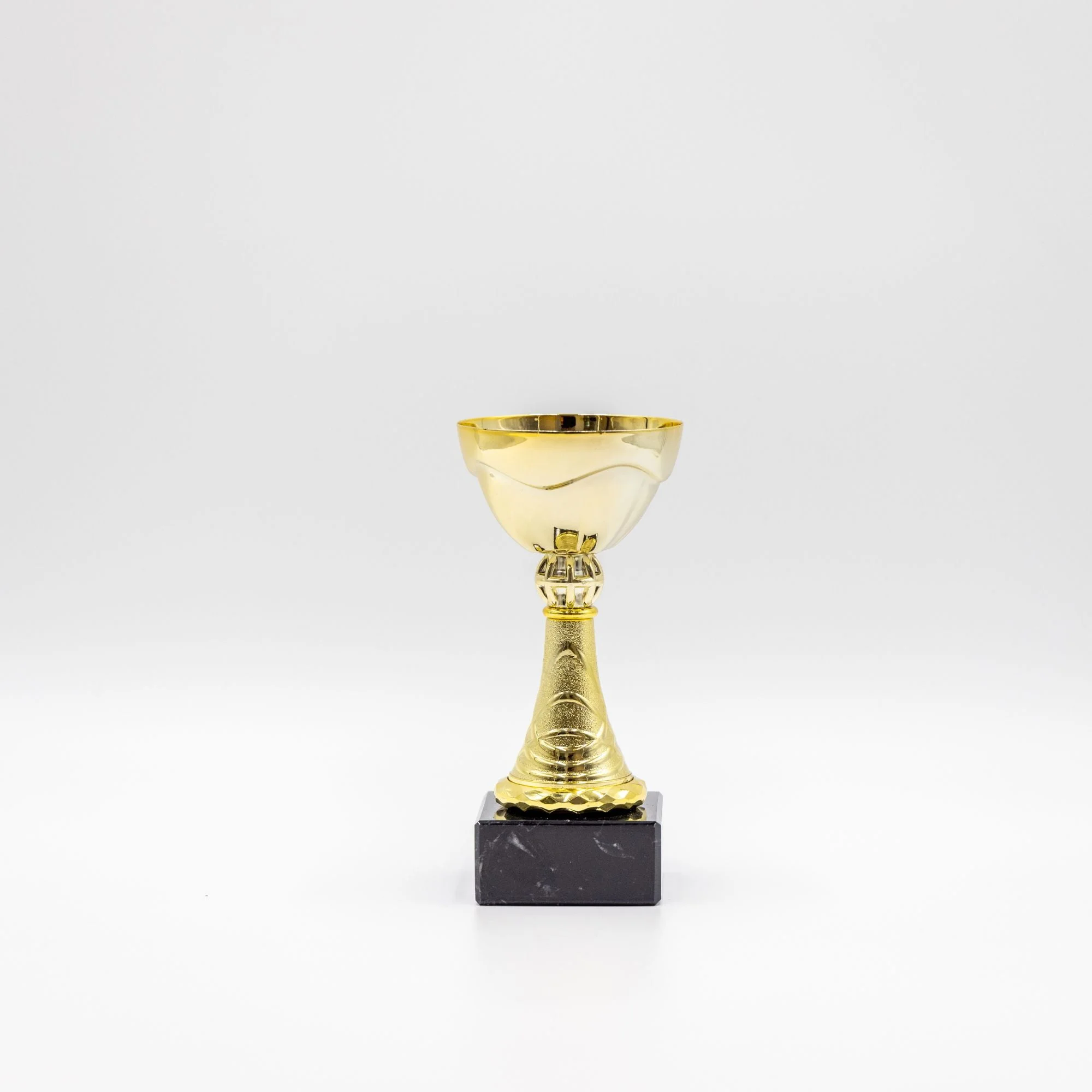 Guldpokal på sort marmorfod mod hvid baggrund