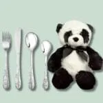 Bestik og plys-panda på grøn baggrund