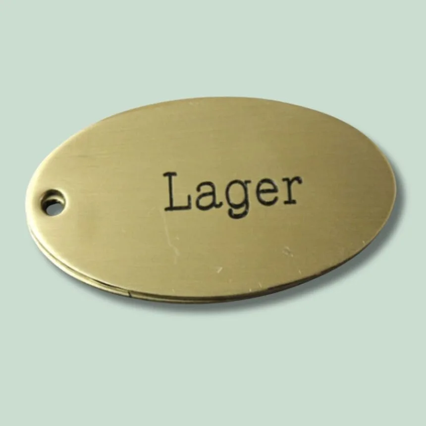 Messingnøgleskilt med indgraveret tekst "Lager