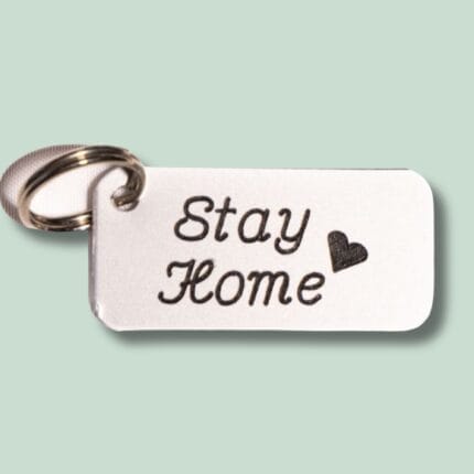 Nøglering med metalmærke indgraveret “Stay Home” og hjerte