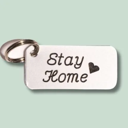 Nøglering med metalmærke indgraveret “Stay Home” og hjerte