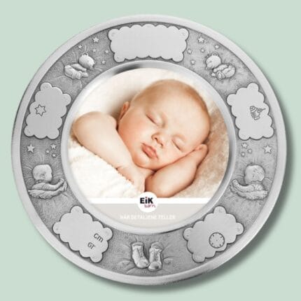 Sølvramme med sovende baby og dekorative motiver.