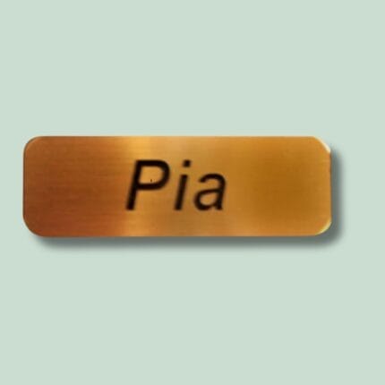 Guld navneskilt med teksten 'Pia'.