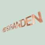 Kobbertekst 'VED STRANDEN' på lys baggrund
