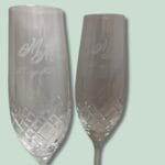 To indgraverede champagneglas på lysegrøn baggrund.