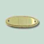 Oval, gylden metalplade med dekorative kanter.