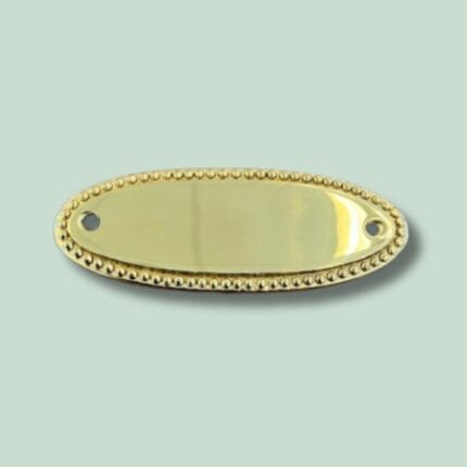 Oval, gylden metalplade med dekorative kanter.