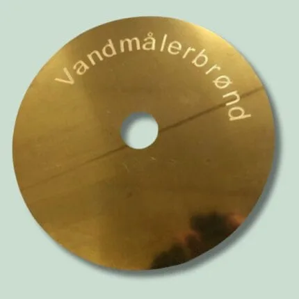 Rund messingplade med tekst: Vandmålerbrønd