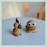 To træfigurer med store øjne på blå overflade.