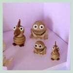 Træfigurer med øjne på lyserød hylde.