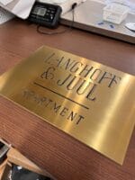 Langhoff & Juul lejlighedsskilt på træbord