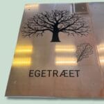 Kobberskilt med egetræ og ordet 'Egetræet' på dansk.