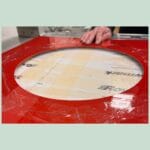 Person arbejder med rød plade med cirkelformet udskæring.