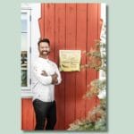 Smilende kok foran femstjernet hotel.