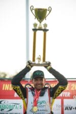 Speedwaykører fejrer med stor pokal og medalje.