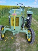 Grøn Bautz traktor på grusvej ved rapsmark.