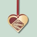 Guld julehjerte ornament med rødt bånd.
