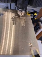 CNC-maskine graverer menneskelige figurer i metalplade.