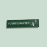 Grønt skilt med teksten 'Hjertestarter' og ikon.